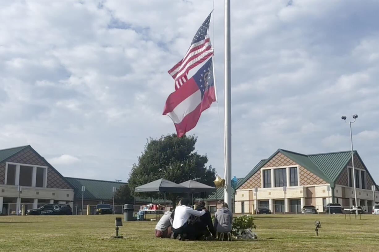 People gather at the flagpole outside the entrance to Apalachee High School on Thursday, Sept. 5, 2024 in Winder, Ga.,  a day after deadly shootings at the school.