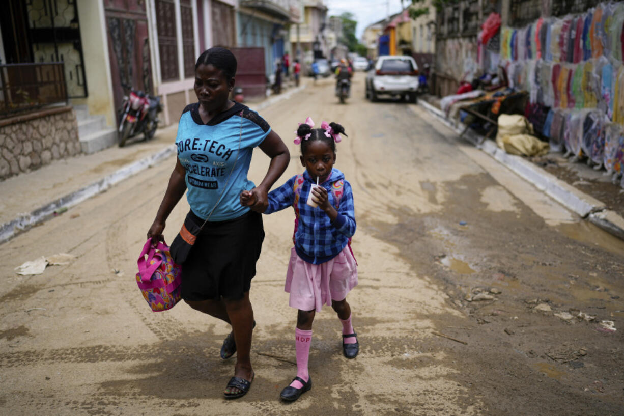 FILE - A child sips on a refreshment as she is walked home from school, in Cap-Haitien, Haiti, April 17, 2024.