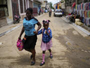 FILE - A child sips on a refreshment as she is walked home from school, in Cap-Haitien, Haiti, April 17, 2024.