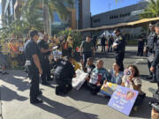 In this photo provided by Ashley Young, Honolulu police officers talk to demonstrators sitting outside a medical center in Honolulu, Monday, Sept. 23, 2024, where unionized nurses have been locked out since going on a one-day strike.