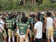 Evergreen football players huddle around head coach Christian Swain, middle, following the Plainsmen's 49-0 win over North Thurston on Friday, Sept. 20, 2024, at McKenzie Stadium.