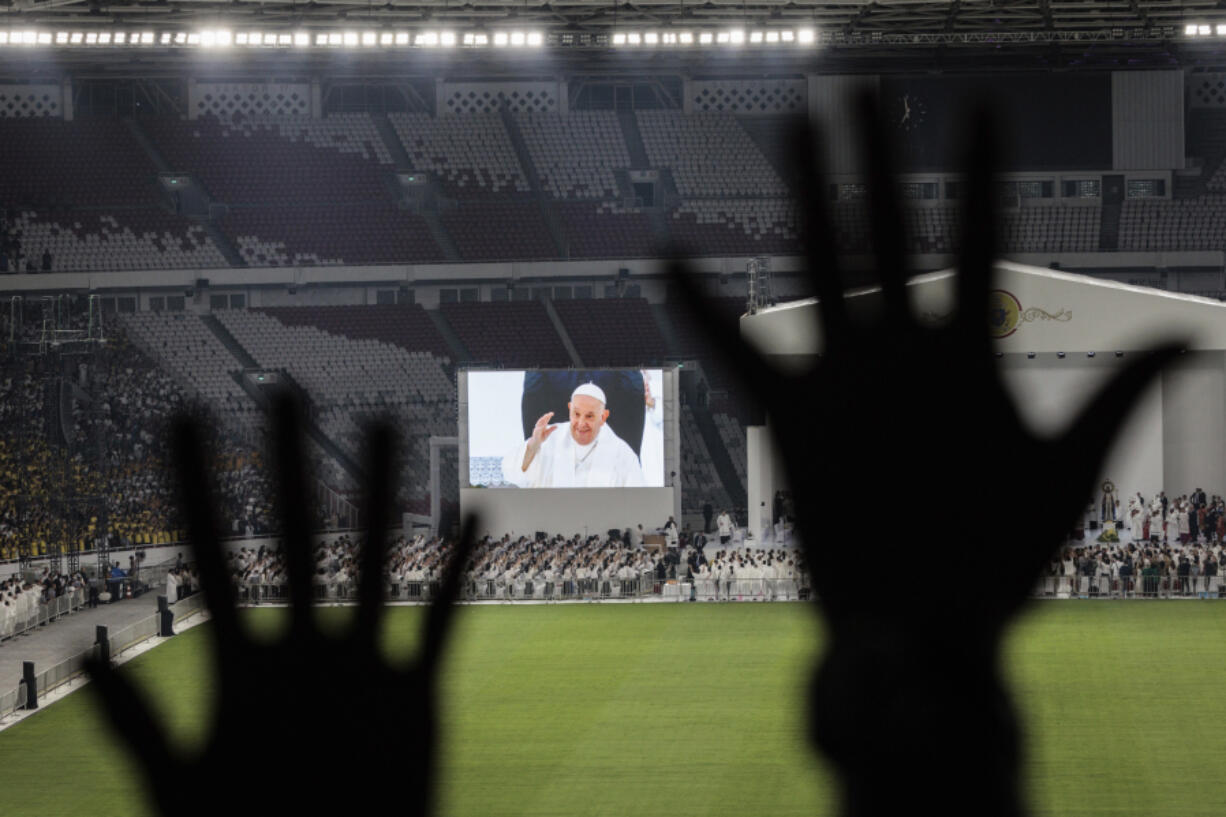 Catholic faithful attend a holy mass led by Pope Francis, shown on the screen, at the Gelora Bung Karno Stadium, in Jakarta, Thursday, Sept. 5, 2024.