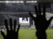 Catholic faithful attend a holy mass led by Pope Francis, shown on the screen, at the Gelora Bung Karno Stadium, in Jakarta, Thursday, Sept. 5, 2024.