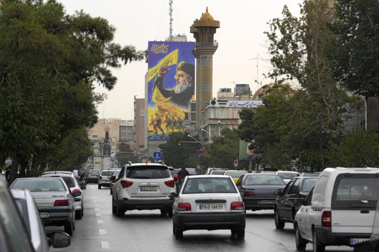 Vehicles drive under a huge portrait of slain Hezbollah leader Hassan Nasrallah, in downtown Tehran, Iran, Monday, Sept. 30, 2024.