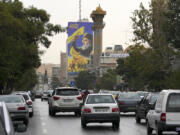 Vehicles drive under a huge portrait of slain Hezbollah leader Hassan Nasrallah, in downtown Tehran, Iran, Monday, Sept. 30, 2024.