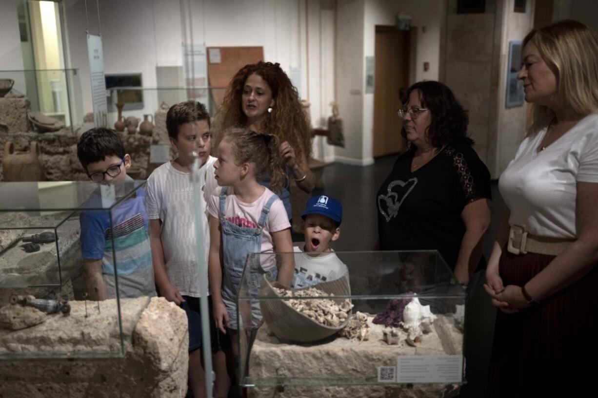 Ariel Heller, 4, center, yawns during the end of a special tour after the child accidentally broke an ancient jar at the Reuben and Edith Hecht Museum in Haifa, Israel, Friday, Aug. 30, 2024. The boy who accidentally broke a rare 3,500-year-old jar in an Israeli museum has been forgiven and invited back, as curators hope to turn the disaster into a teachable moment.