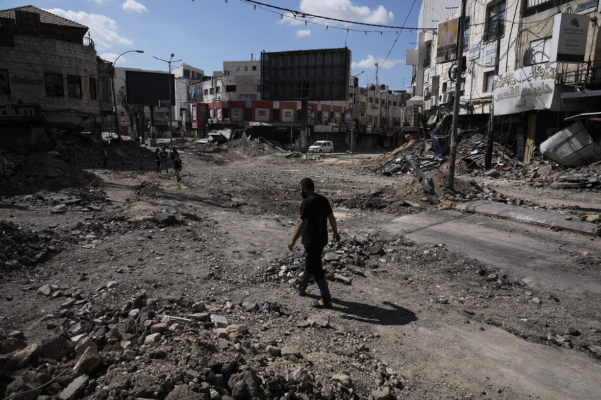 People walk between rubbles following an Israeli army raid in Jenin, West Bank, on Wednesday, Sept. 4, 2024.