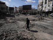 People walk between rubbles following an Israeli army raid in Jenin, West Bank, on Wednesday, Sept. 4, 2024.