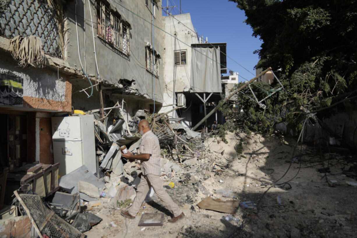 Palestinian refugees walk outside their partly destroyed houses in the West Bank refugee camp of Tulkarem, during an Israeli army operation in Tulkarem, Thursday, Sept. 12, 2024.