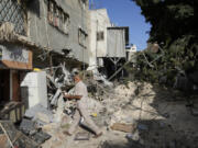 Palestinian refugees walk outside their partly destroyed houses in the West Bank refugee camp of Tulkarem, during an Israeli army operation in Tulkarem, Thursday, Sept. 12, 2024.