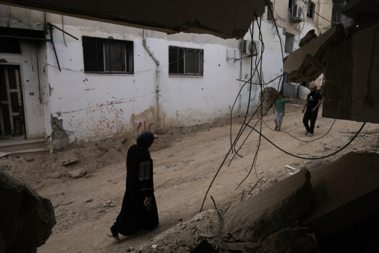 Palestinians walk past a damaged building following an Israeli military operation in the West Bank city of Jenin on Friday, Sept. 6, 2024.