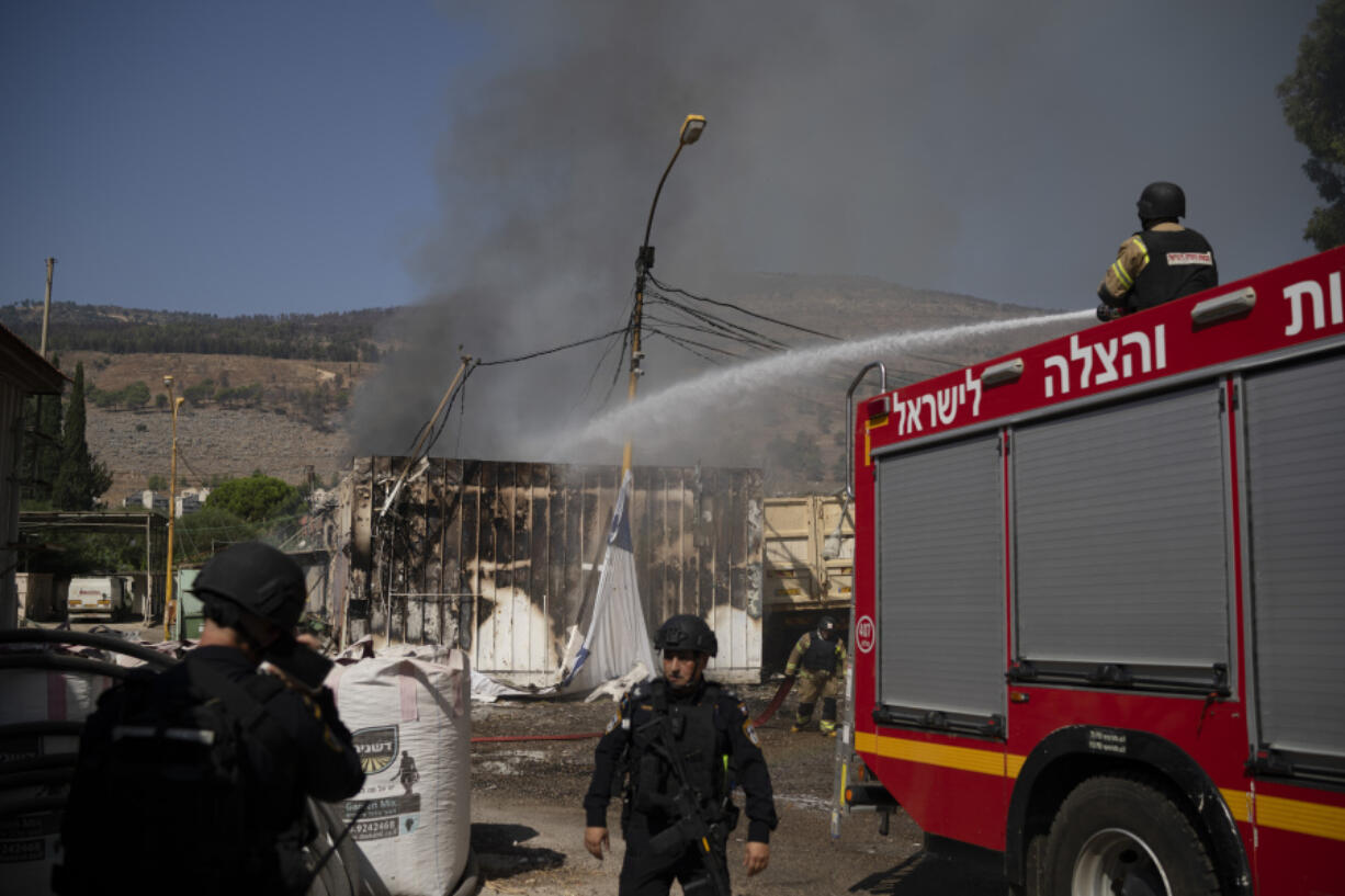 Firefighters work to extinguish a fire after a rocket, fired from Lebanon, hit a local municipality storage in Kiryat Shmona, northern Israel, Tuesday, Sept. 24, 2024.