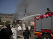 Firefighters work to extinguish a fire after a rocket, fired from Lebanon, hit a local municipality storage in Kiryat Shmona, northern Israel, Tuesday, Sept. 24, 2024.