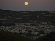 The supermoon rises behind the houses in Mas&#039;ade, a village in the Israeli-annexed Golan Heights, Tuesday, Sept. 17, 2024.