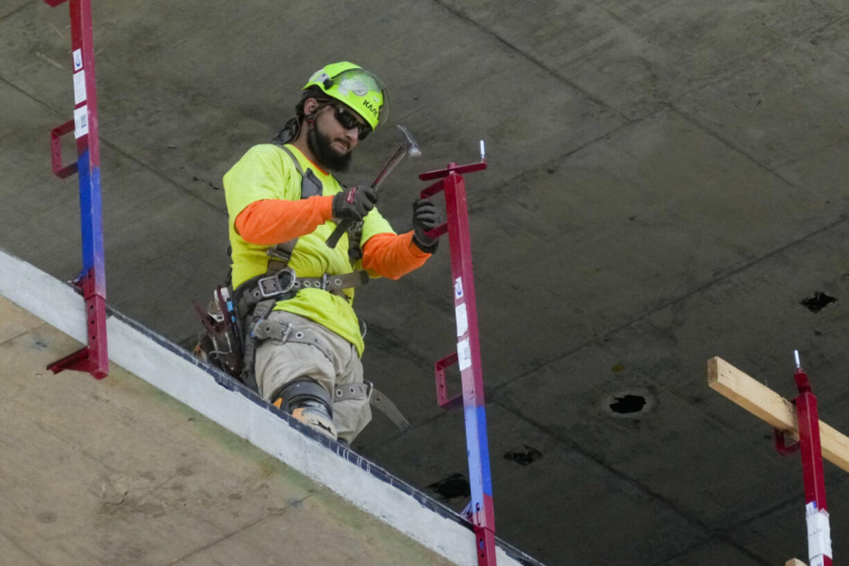 A construction worker installs a safety railing on a new building in Philadelphia, Tuesday, Sept. 3, 2024.