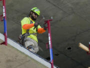 A construction worker installs a safety railing on a new building in Philadelphia, Tuesday, Sept. 3, 2024.