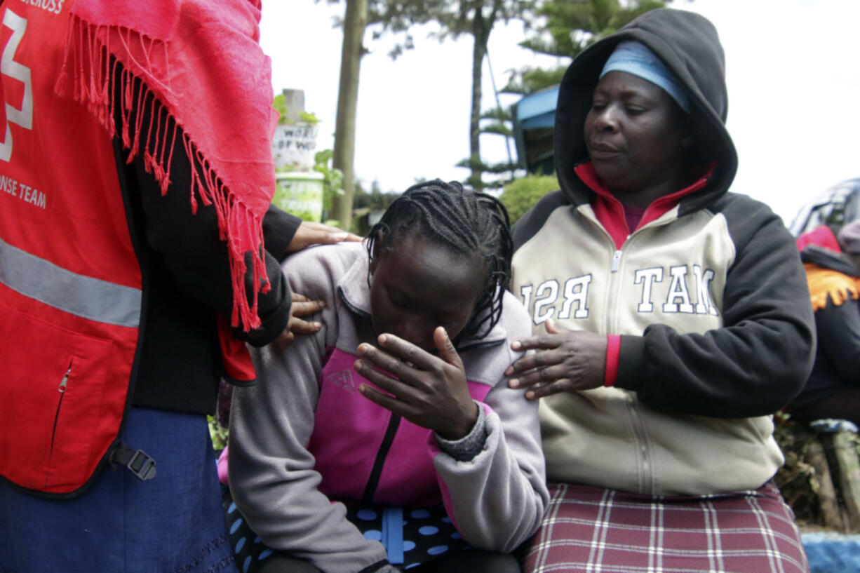 Kenya Red Cross personnel and relatives try to comfort a woman reacting near a burned-out dormitory, following a fire at the Hillside Endarasha Primary in Nyeri, Kenya Friday, Sep. 6, 2024.