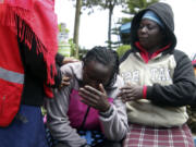 Kenya Red Cross personnel and relatives try to comfort a woman reacting near a burned-out dormitory, following a fire at the Hillside Endarasha Primary in Nyeri, Kenya Friday, Sep. 6, 2024.