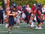 King's Way sophomore quarterback Owen Paulsen (12) rolls out while looking for a receiver downfield against Hoquiam on Friday, Sept. 13, 2024.