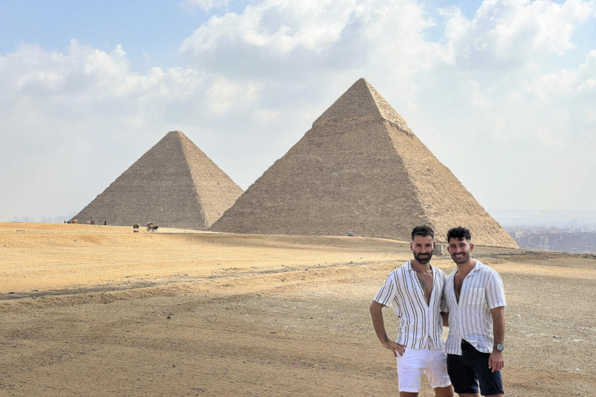 This 2023 photo shows Stefan Arestis, right, and Sebastien Chaneac, at the Pyramids in Egypt. The two are globetrotters who run the LGBTQ+-focused travel blog The Nomadic Boys.