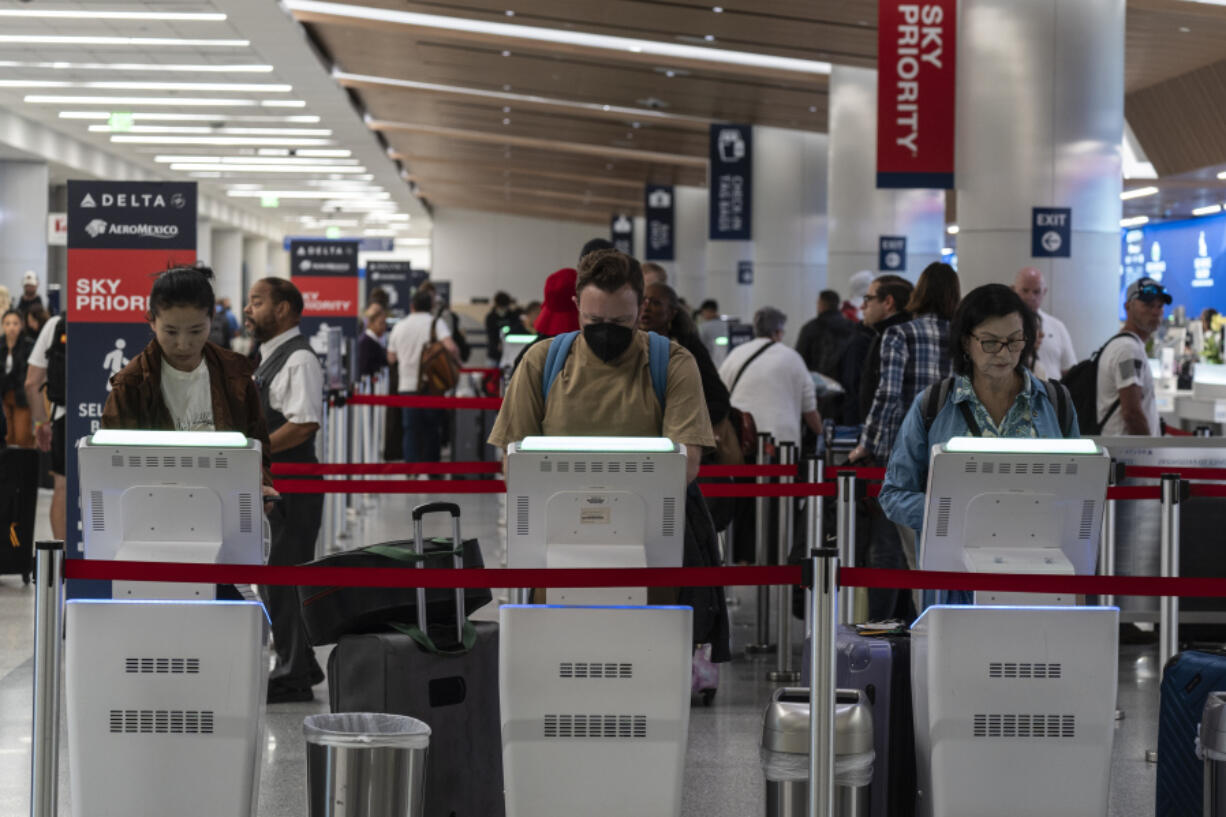 Travelers use kiosks to check in for flights in the Delta Airlines ticketing area at the Los Angeles International Airport in Los Angeles, Friday, Aug. 30, 2024. (AP Photo/Jae C.