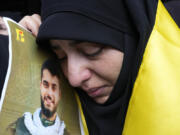 A woman holds a picture of a Hezbollah member who was killed on Wednesday when a handheld device exploded, during his funeral procession in the southern suburbs of Beirut, Thursday, Sept. 19, 2024.