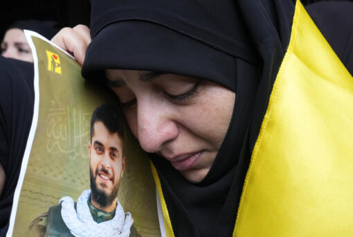 A woman holds a picture of a Hezbollah member who was killed on Wednesday when a handheld device exploded, during his funeral procession in the southern suburbs of Beirut, Thursday, Sept. 19, 2024.