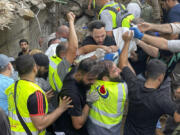 Rescuers carry a body at the scene of a missile strike in the southern suburbs of Beirut, Friday, Sept. 20, 2024.