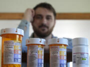 Cancer patient Steven Manetta sits for a portrait Monday, Sept. 9, 2024, in his Lemont, Ill., home with four of the five medicines he takes daily to battle the nausea from his chemotherapy.