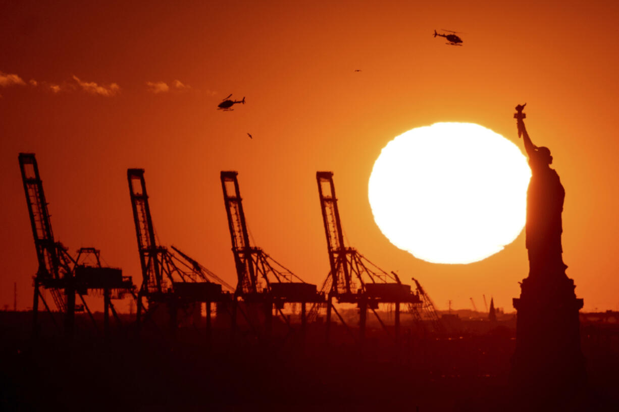 FILE - Cranes at the Port of New York and New Jersey appear behind the Statue of Liberty, Nov. 20, 2022, in a photo taken from New York.