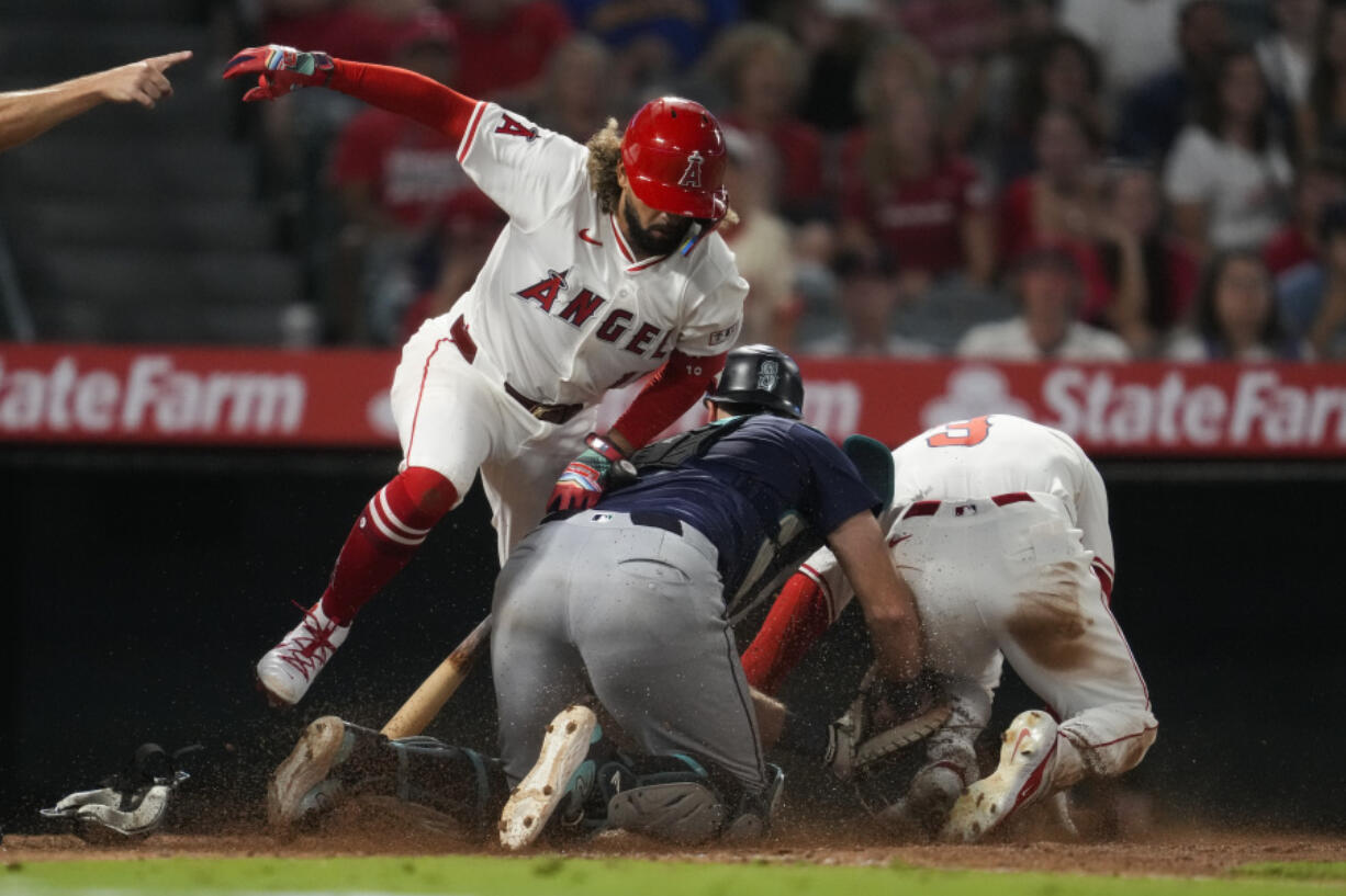 Seattle Mariners catcher Cal Raleigh, center, tags out Los Angeles Angels&#039; Taylor Ward (3) at home after fielding a bunt from Jack L&oacute;pez, left, of a baseball game in Anaheim, Calif., Saturday, Aug. 31, 2024. Lopez was out at first.