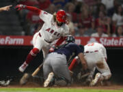 Seattle Mariners catcher Cal Raleigh, center, tags out Los Angeles Angels&#039; Taylor Ward (3) at home after fielding a bunt from Jack L&oacute;pez, left, of a baseball game in Anaheim, Calif., Saturday, Aug. 31, 2024. Lopez was out at first.