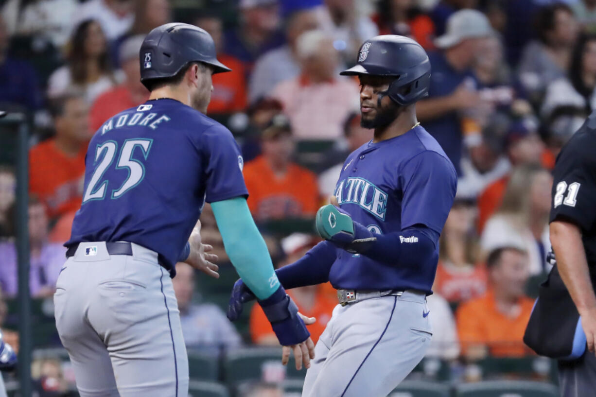 Seattle Mariners&#039; Dylan Moore (25) and Victor Robles, right, celebrate after they both scored on a two-run RBI single by Justin Turner against the Houston Astros during the sixth inning of a baseball game Wednesday, Sept. 25, 2024, in Houston.