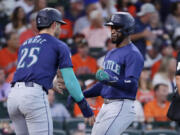 Seattle Mariners&#039; Dylan Moore (25) and Victor Robles, right, celebrate after they both scored on a two-run RBI single by Justin Turner against the Houston Astros during the sixth inning of a baseball game Wednesday, Sept. 25, 2024, in Houston.