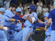 Texas Rangers&#039; Marcus Semien, center wearing a helmet, is congratulated by teammates after hitting a single that scored Leody Taveras during the ninth inning of a baseball game against the Seattle Mariners Sunday, Sept.