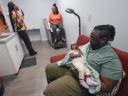 Jennie Joseph, back left, lead midwife and clinic director at the Commonsense Childbirth clinic talks with client Regine Baramore as husband Scott holds six-week-old daughter, Yahareice, Wednesday, June 26, 2024, in Orlando, Fla.