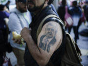 FILE - A supporter of Mexican President Andres Manuel Lopez Obrador sporting a tattoo of the president arrives for a march to show support for Lopez Obrador&rsquo;s administration in Mexico City, Nov. 27, 2022.