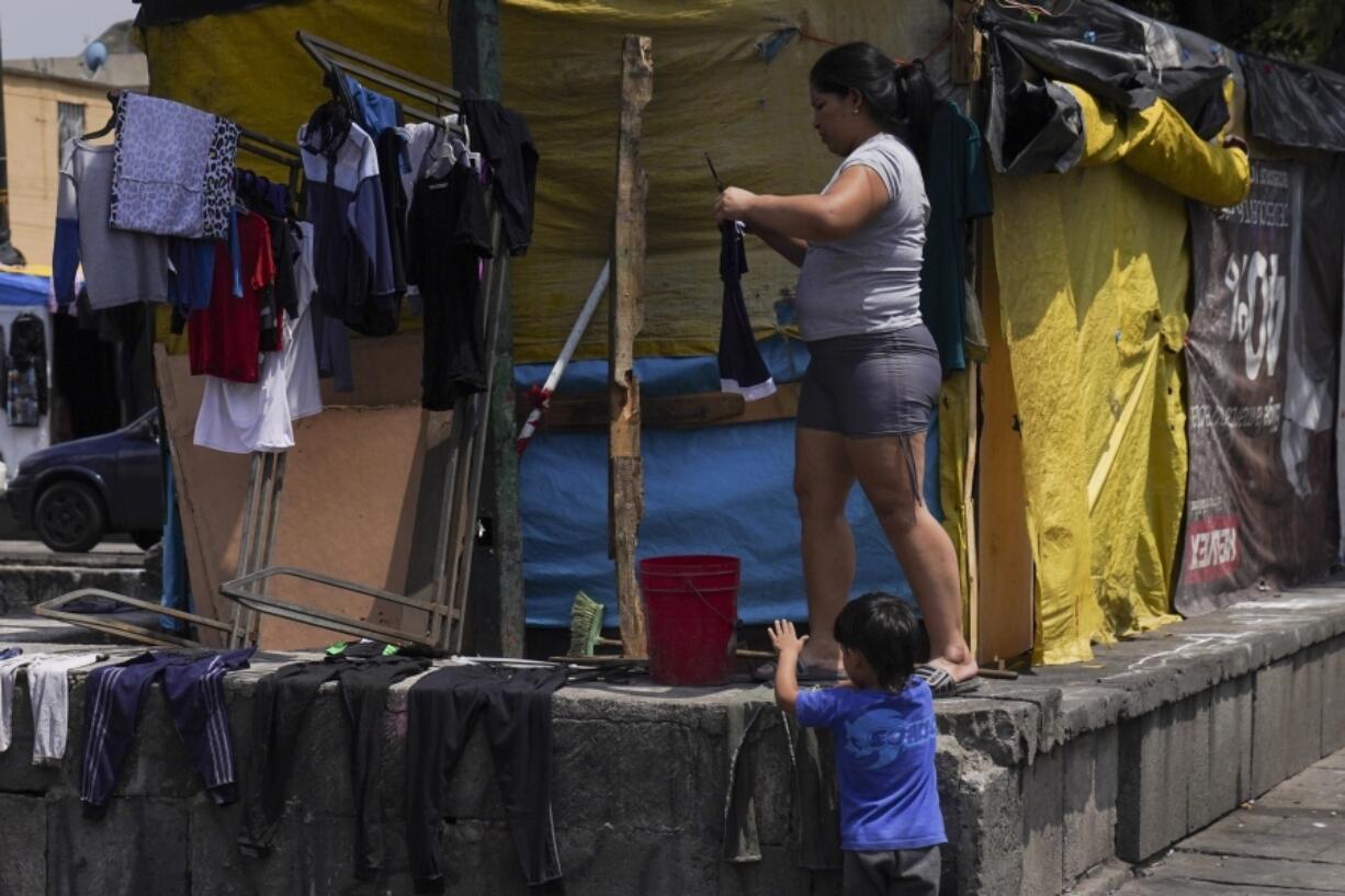 Venezuelan migrant Osdeigly Granadillo hangs her clothes to dry at a migrant tent encampment set up on the perimeters surrounding the Santa Cruz y La Soledad Catholic parish church, in La Merced neighborhood of Mexico City, July 16, 2024.