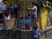 Venezuelan migrant Osdeigly Granadillo hangs her clothes to dry at a migrant tent encampment set up on the perimeters surrounding the Santa Cruz y La Soledad Catholic parish church, in La Merced neighborhood of Mexico City, July 16, 2024.