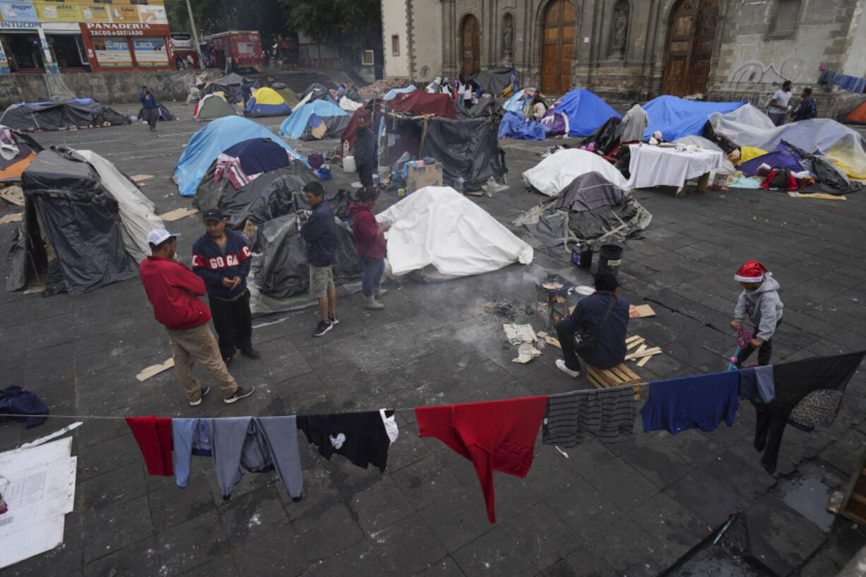 FILE - Migrants gather at a tent encampment set up on the plaza of the Santa Cruz y La Soledad Catholic parish church, in La Merced neighborhood of Mexico City, Dec. 26, 2023.