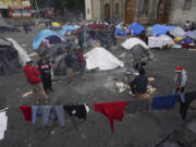 FILE - Migrants gather at a tent encampment set up on the plaza of the Santa Cruz y La Soledad Catholic parish church, in La Merced neighborhood of Mexico City, Dec. 26, 2023.