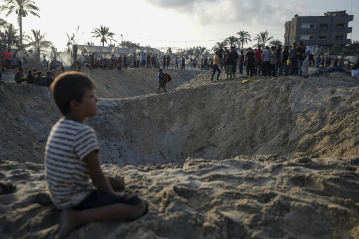 FILE - Palestinians look at the destruction after an Israeli airstrike on a crowded tent camp housing Palestinians displaced by the war in Muwasi, Gaza Strip, Sept. 10, 2024.