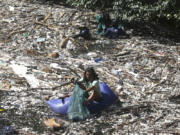 FILE - A volunteer picks up trash on a river which is covered with trash at Pecatu, Bali, Indonesia, March 22, 2024.