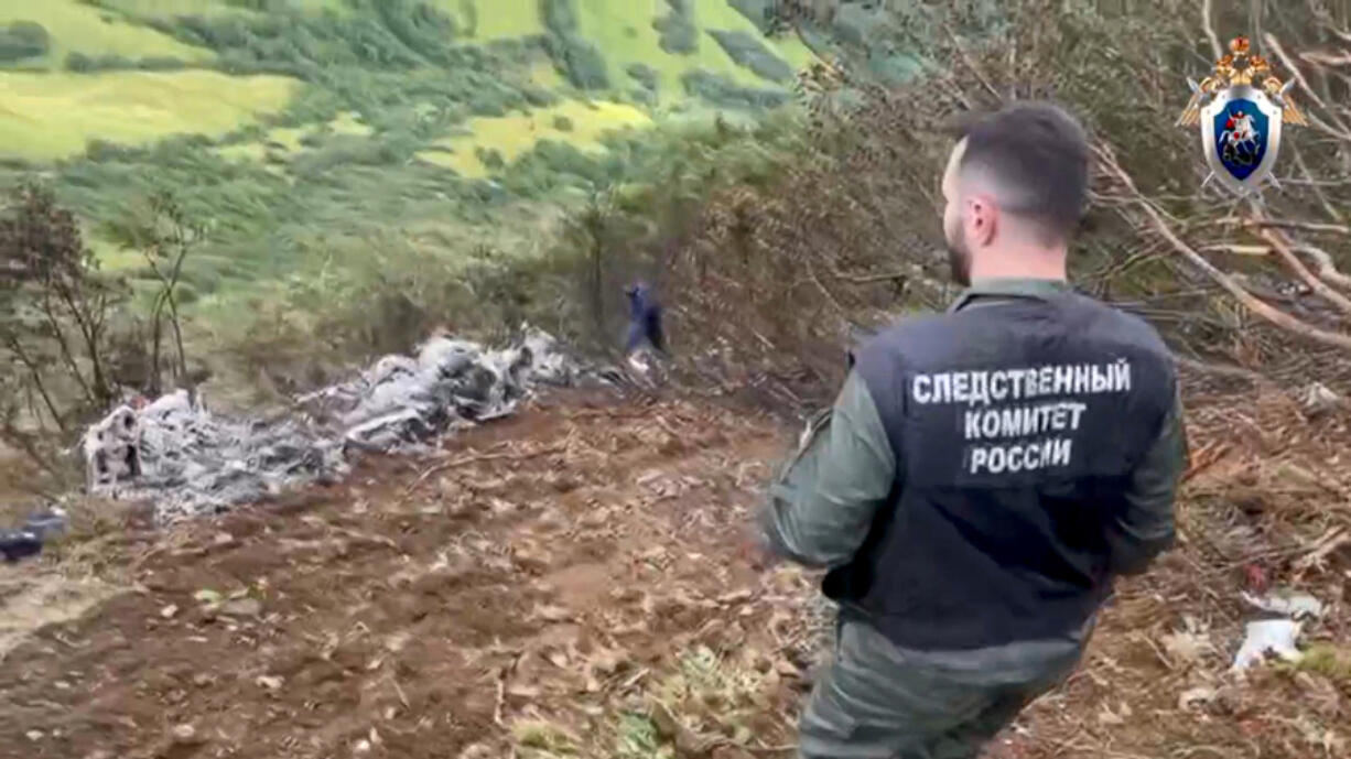 In this photo taken from video released by Investigative Committee of Russia on Monday, Sept. 2, 2024, A Russian Investigative Committee employee works at the crash site of the Mi-8 helicopter that was carrying 19 passengers and three crew members on board in Kamchatka region of Russia&#039;s Far East.