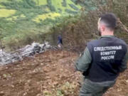 In this photo taken from video released by Investigative Committee of Russia on Monday, Sept. 2, 2024, A Russian Investigative Committee employee works at the crash site of the Mi-8 helicopter that was carrying 19 passengers and three crew members on board in Kamchatka region of Russia&#039;s Far East.