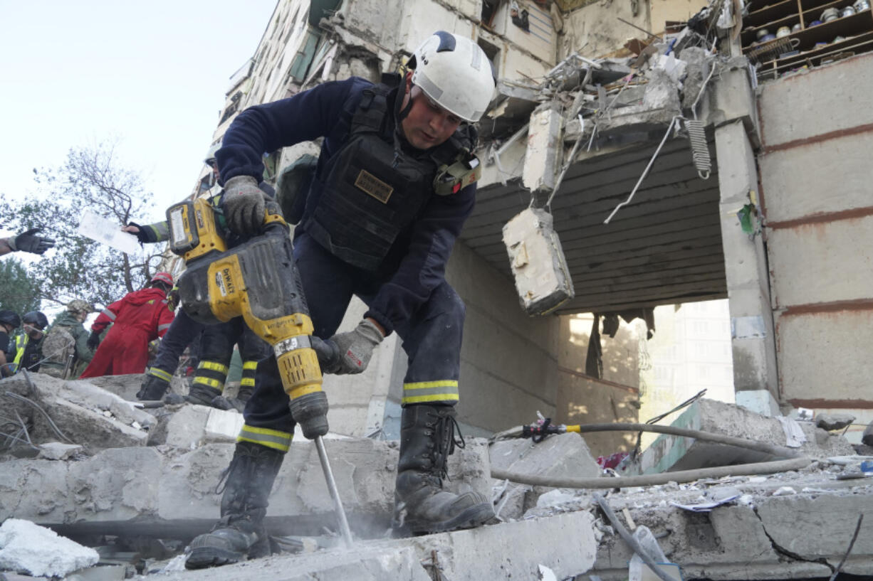 An emergency worker tries to shift the rubble and debris after a Russian attack that hit a residential building in Kharkiv, Ukraine, Tuesday Sept. 24, 2024.