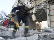 An emergency worker tries to shift the rubble and debris after a Russian attack that hit a residential building in Kharkiv, Ukraine, Tuesday Sept. 24, 2024.