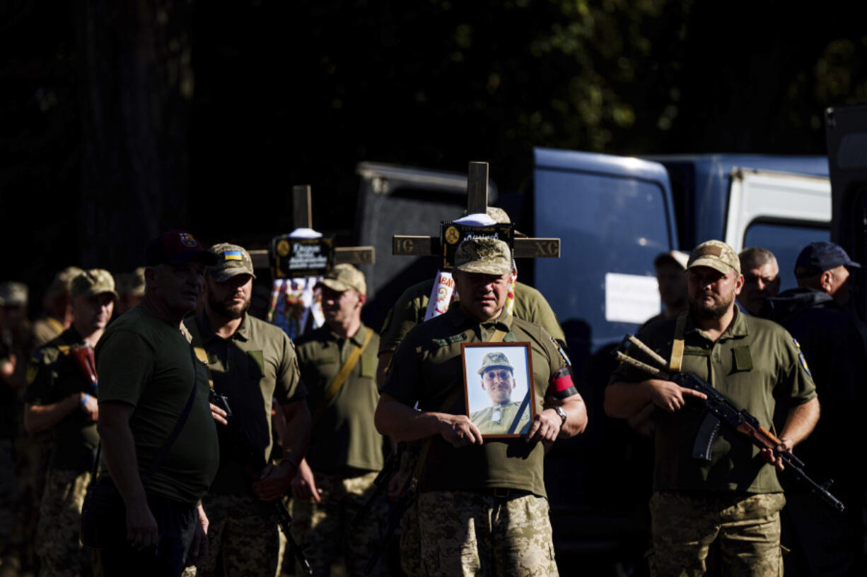 Ukrainian servicemen carry crosses and pictures of their comrades killed in a Russian rocket attack at a Ukrainian military academy, during their funeral ceremony in Poltava, Ukraine, Saturday Sept. 7, 2024.