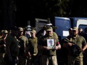 Ukrainian servicemen carry crosses and pictures of their comrades killed in a Russian rocket attack at a Ukrainian military academy, during their funeral ceremony in Poltava, Ukraine, Saturday Sept. 7, 2024.