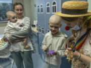 Tetiana Nosova, who goes by the clown name of Zhuzha, a volunteer from the &quot;Bureau of Smiles and Support&quot; plays a ukulele as she stands with Michael Bilyk, who is held by his mother Antonina Malyshko, and Kira Vertetska, 8, at Okhmatdyt children&#039;s hospital in Kyiv, Ukraine, Thursday Sept. 19, 2024.